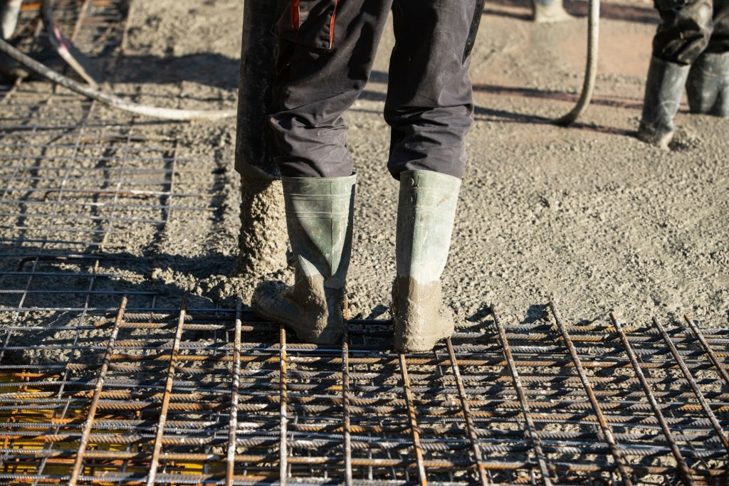 Бетонщик заливает фундаментную плиту бетонной смесью на граните марки М700 класса б50 в Одинцово